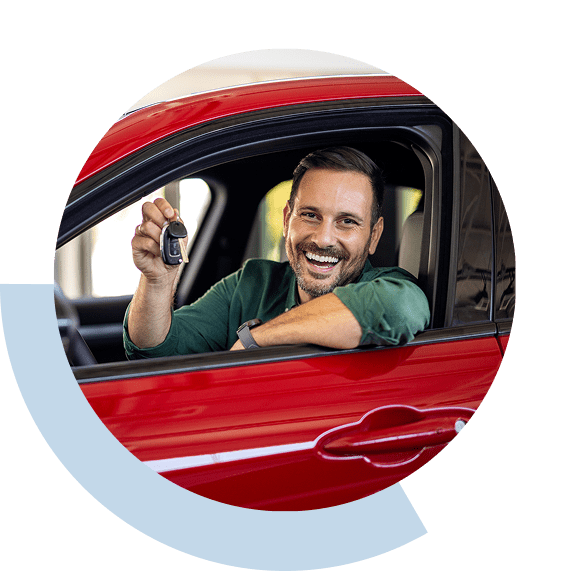 Happy man in red car holding car key and smiling.