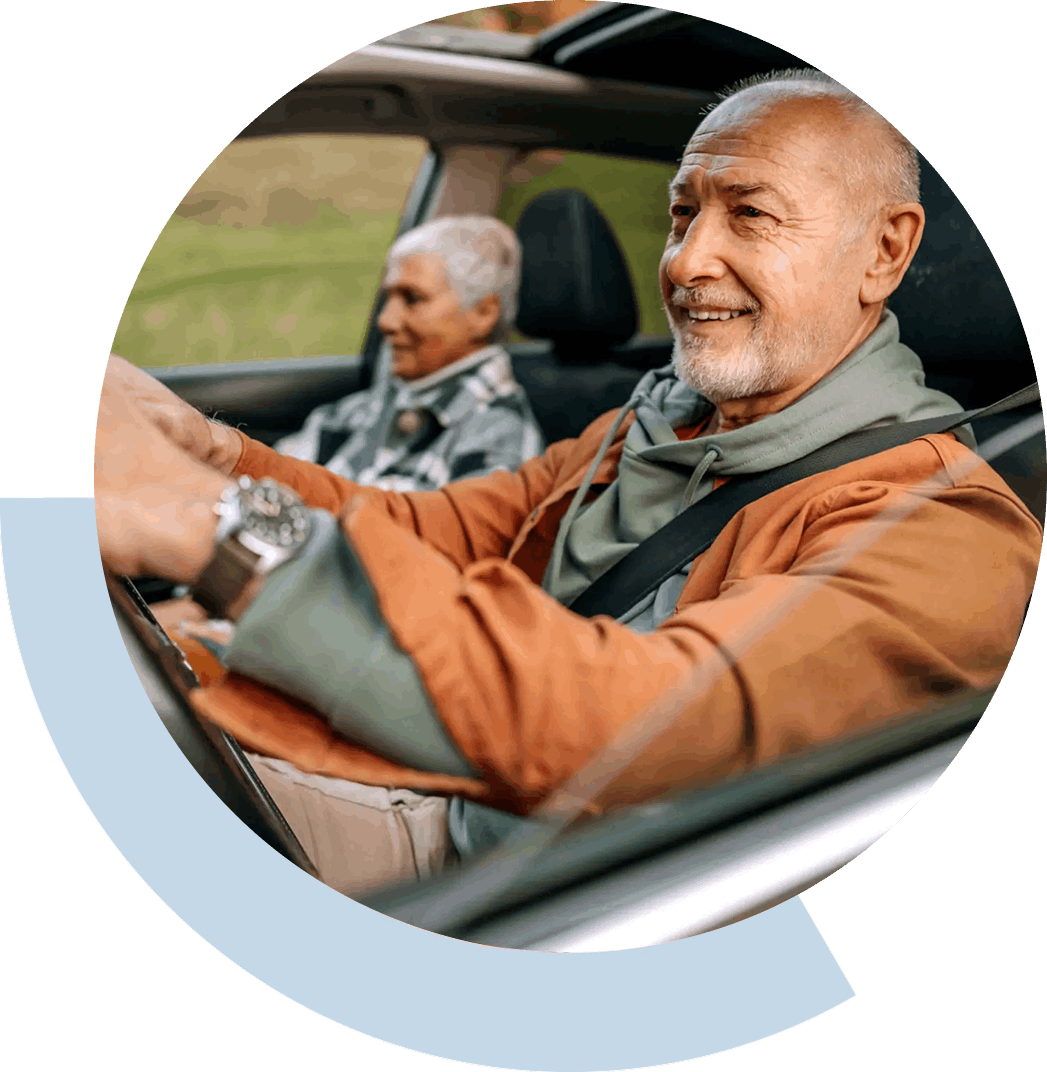 Two older men smiling while driving in a car.